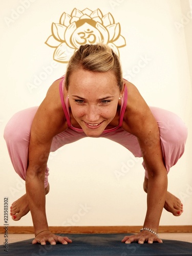 Young beautiful girl doing a yoga pose kakasana in a pink sport dress. photo