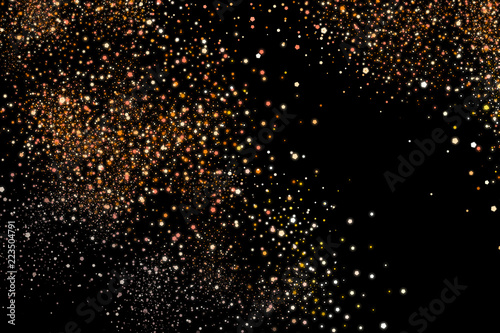 Golden explosion of confetti. Shiny dust, amber particles, lots of bright stars. Gold glitter texture isolated on black, celebration background