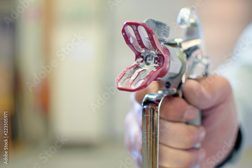 фотографія Close up of man holding a used airless paint spray gun.