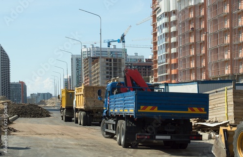 Trucks, construction machinery and high-rise cranes on the construction site.