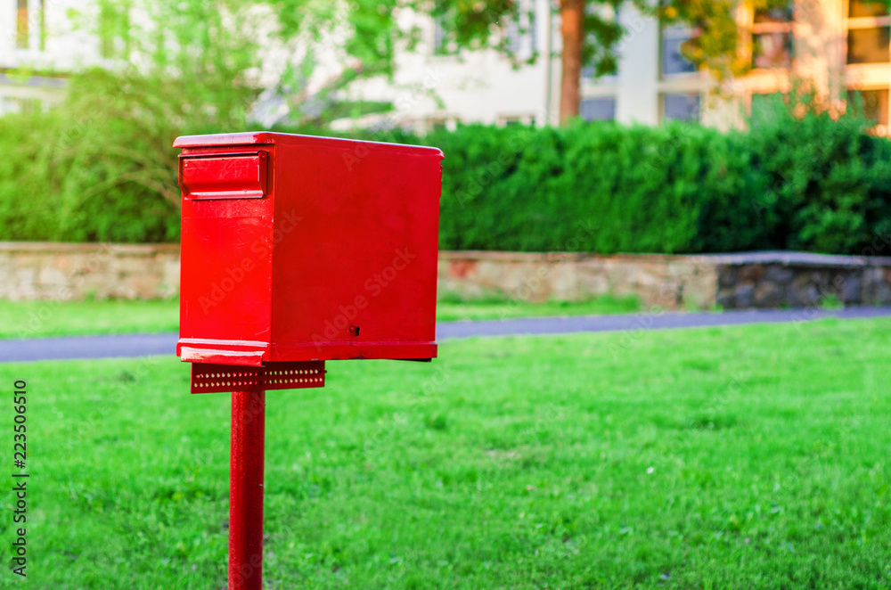 Mailbox red color on a column on a green background Mailbox red color on a column on a green background