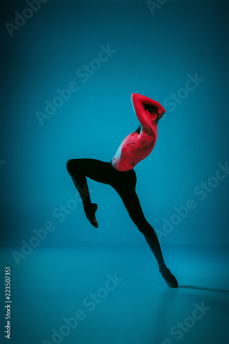 The male athletic ballet dancer performing dance on dark blue background. Studio shot. Ballet concept. Fit young man. Caucasian model © master1305