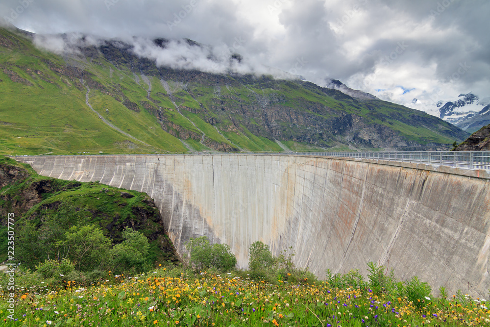 Beautiful view of the concrete dam of the reservoir lake Lac de Moiry in the alps near Grimentz, Switzerland, on a cloudy summer day
