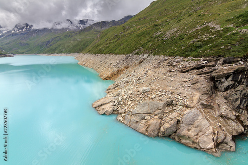 Beautiful view of reservoir lake Moiry (lac de Moiry) with vibrant turquoise blue water at a low level in summer in Valais, Switzerland