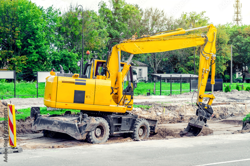 Large yellow excavator digs a hole, repairs the road, heavy equipment, road works. Large yellow excavator digs a hole, repairs the road, heavy equipment, road works.