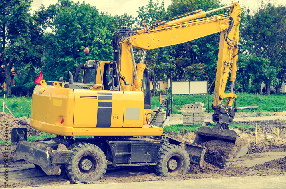 Large yellow excavator digs a hole, repairs the road, heavy equipment, road works. Large yellow excavator digs a hole, repairs the road, heavy equipment, road works.