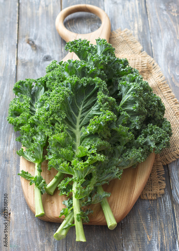 Fresh green curly kale leaves on a cutting board on a wooden table. selective focus. rustic style. healthy vegetarian food