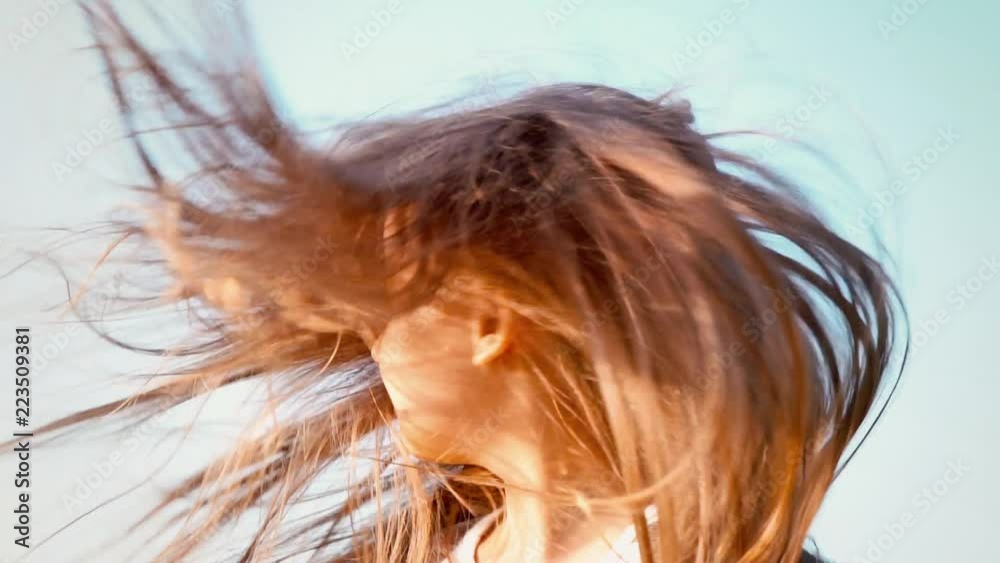 An attractive little girl with long flowing hair twists her head in ...
