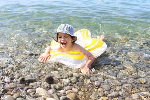 Happy smiling 5 years boy swimming with swimring in the sea photo