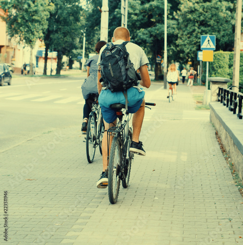 man with a backpack riding a bike on a bike path in the city © romankrykh