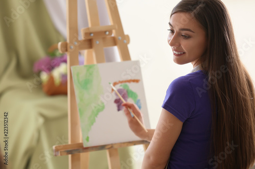 Smiling young woman paintin...