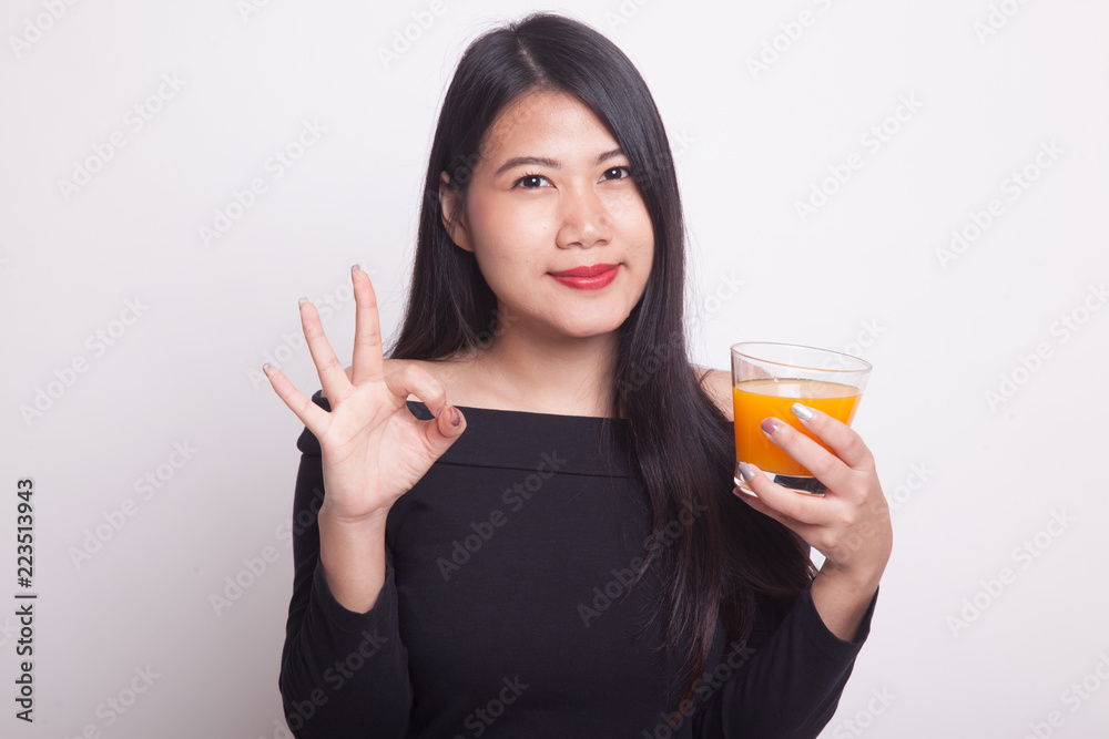 Young Asian woman drink orange juice show OK sign. Young Asian woman drink orange juice show OK sign.