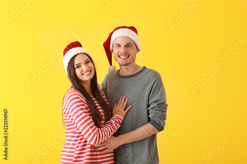 Portrait of cute young couple in Santa hats on color background © Pixel-Shot