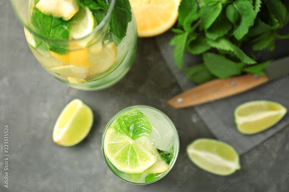 Glass and jug of fresh mojito on grey table Glass and jug of fresh mojito on grey table