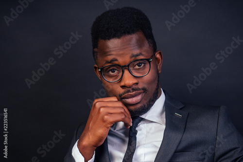 portrait of successful african american businessman company leader in glasses reading a book on black background studio shot