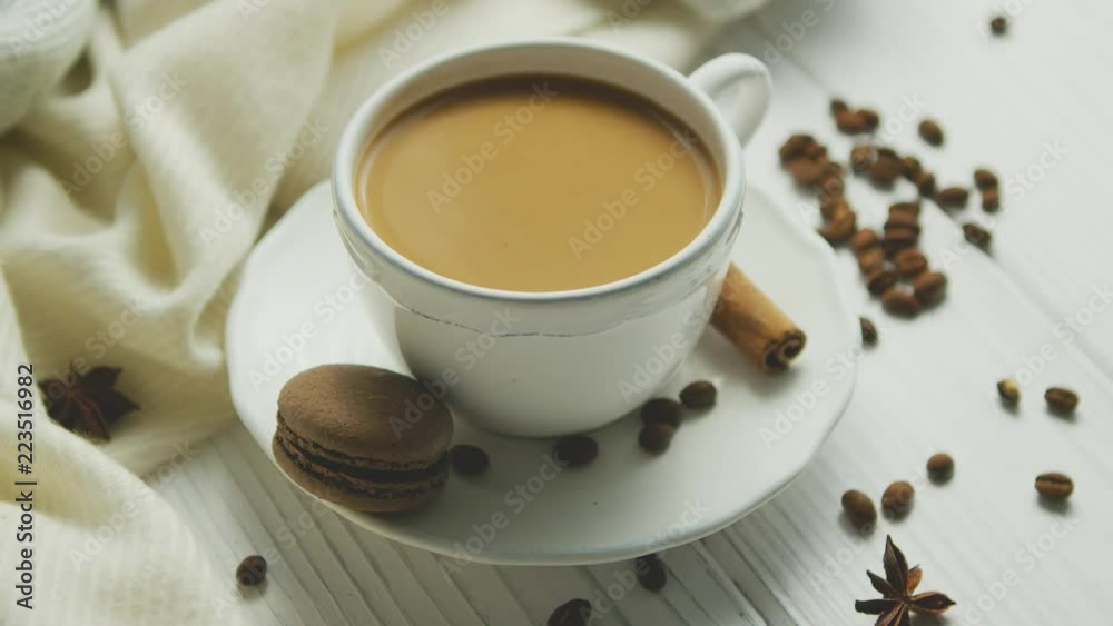 From above view of cup of coffee with biscuit and cinnamon decorated with beans on white wooden background From above view of cup of coffee with biscuit and cinnamon decorated with beans on white wooden background