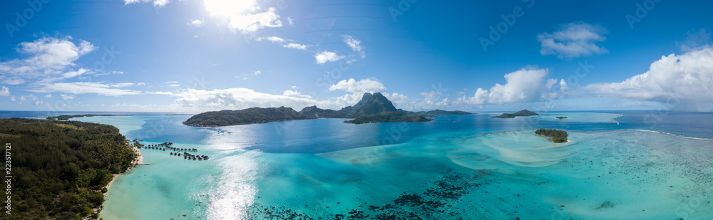 Fototapeta premium Panoramiczny widok z lotu ptaka luksusowych willi nad wodą z palmami, błękitną laguną, białą piaszczystą plażą i górą Otemanu na wyspie Bora Bora, Tahiti, Polinezja Francuska (Bora Bora Aerial)