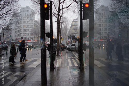 Fototapeta Naklejka Na Ścianę i Meble -  People crossing road on city street in sleet and snow, winter weather, boulevard Magenta, near Gare du Nord, Paris, France