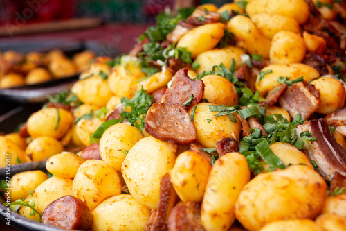 Pile of cooked potatoes mixed with grilled european sausage and parsley. Street food.