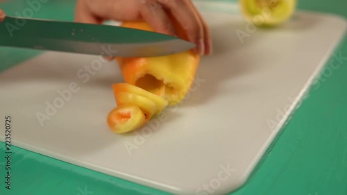 female slices yellow bell pepper. side view of a woman preparing dinner. photo