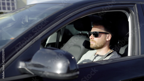 Stylish successful man driving a black luxury car in summer. © kustvideo