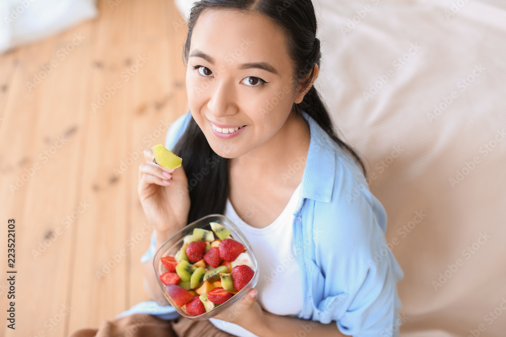 Asian woman eating healthy fruit salad at home Asian woman eating healthy fruit salad at home