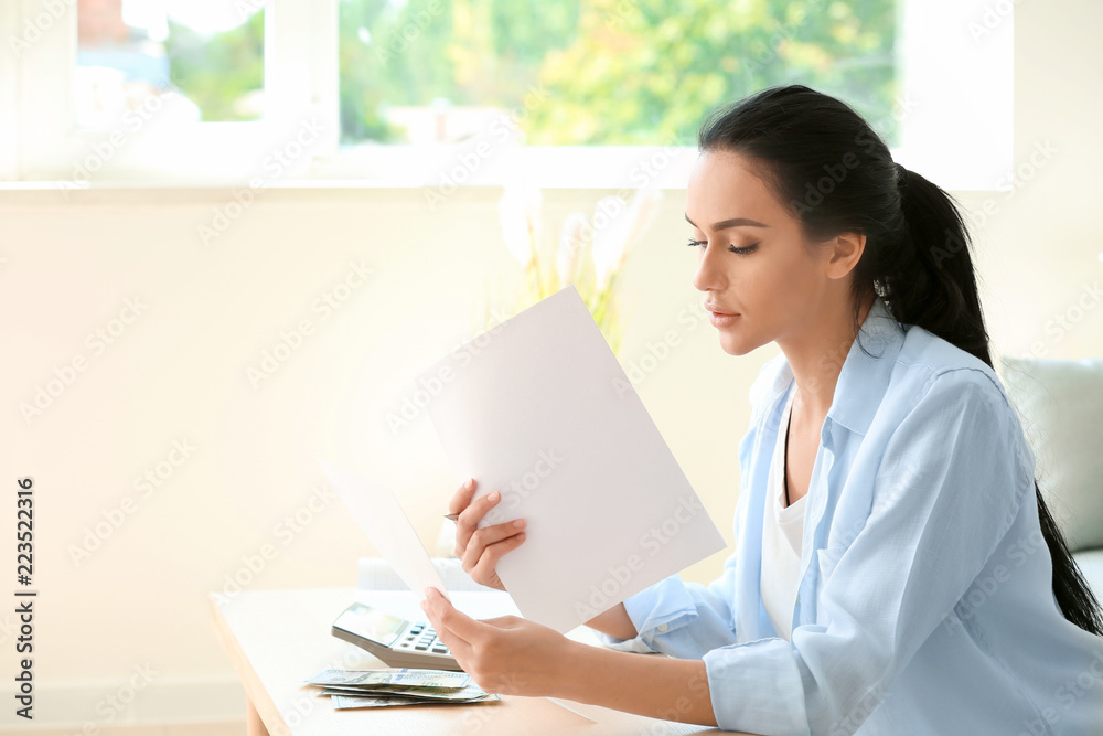 Young woman working with financial papers at table Young woman working with financial papers at table