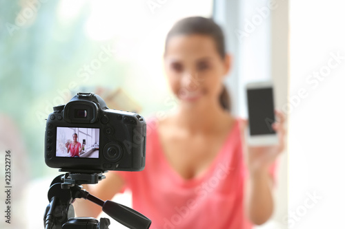 Female blogger with money and mobile phone recording video at home