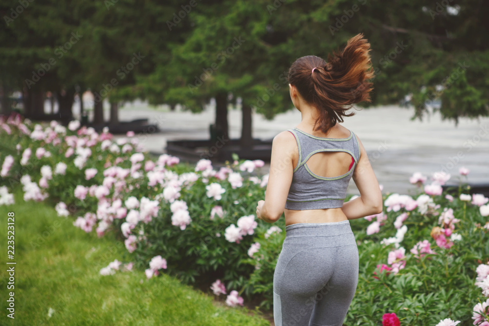 Young woman jogging down a path in a green park. Young woman jogging down a path in a green park.