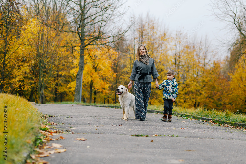 Fototapeta premium Mom and son walking their dog in the park in the fall