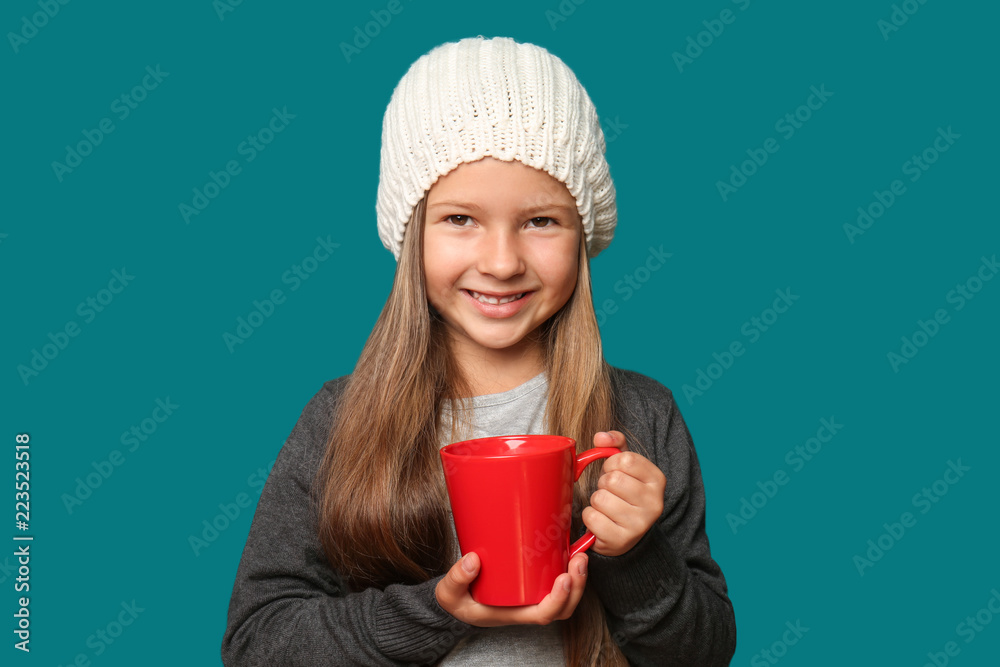 Cute little girl in warm clothes and with cup of hot chocolate on color background Cute little girl in warm clothes and with cup of hot chocolate on color background