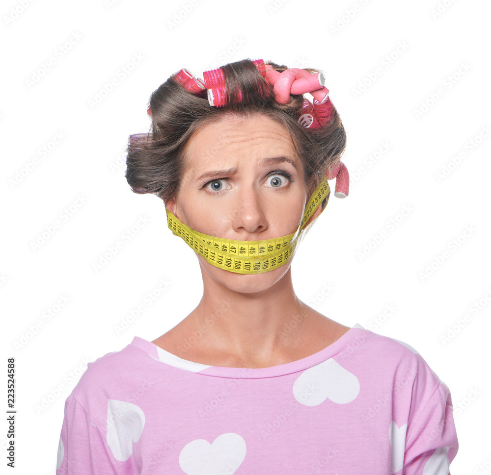 Stressful woman with measuring tape around her mouth on white background. Diet concept Stressful woman with measuring tape around her mouth on white background. Diet concept