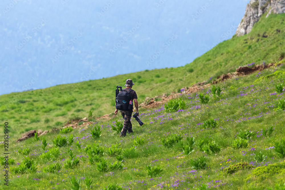 Landscape and wildlife photographer walking on the mountain to find a good place for taking pictures. Man enjoying a walk on mountain colorful peak