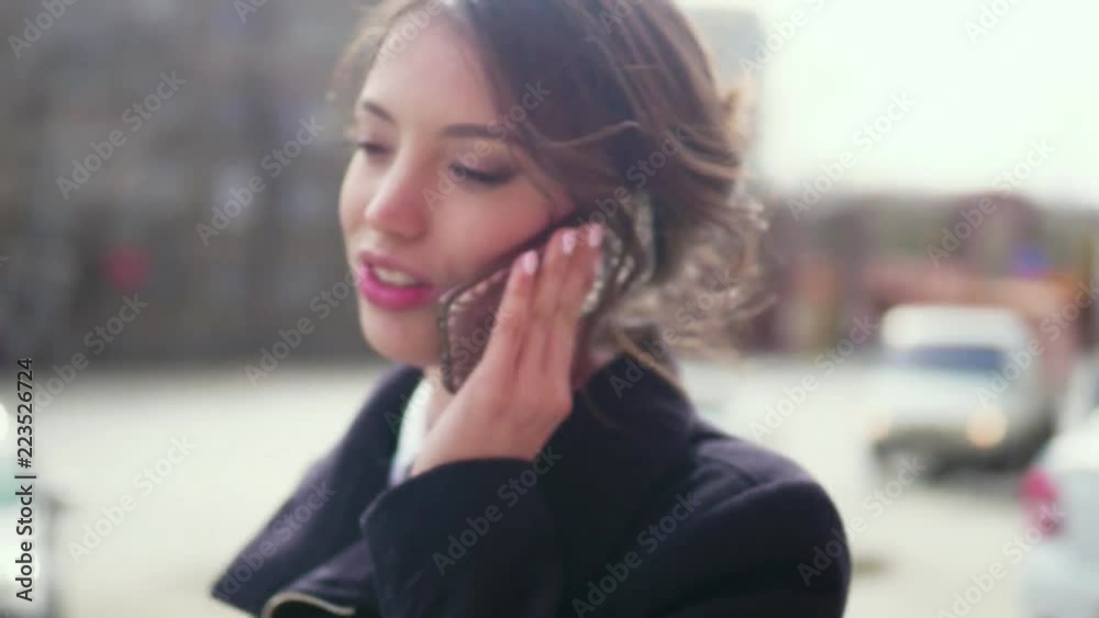 Beautiful woman talking on cellphone by city street. Beautiful woman talking on cellphone by city street.