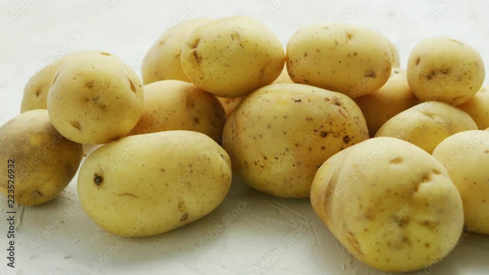 Closeup shot of pile of unpeeled clean potatoes composed on white surface in daylight Closeup shot of pile of unpeeled clean potatoes composed on white surface in daylight