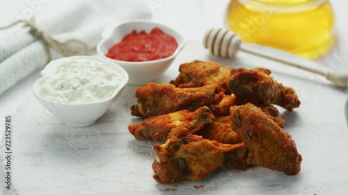 Closeup of golden crispy fried chicken wings served on board with different sauces  photo