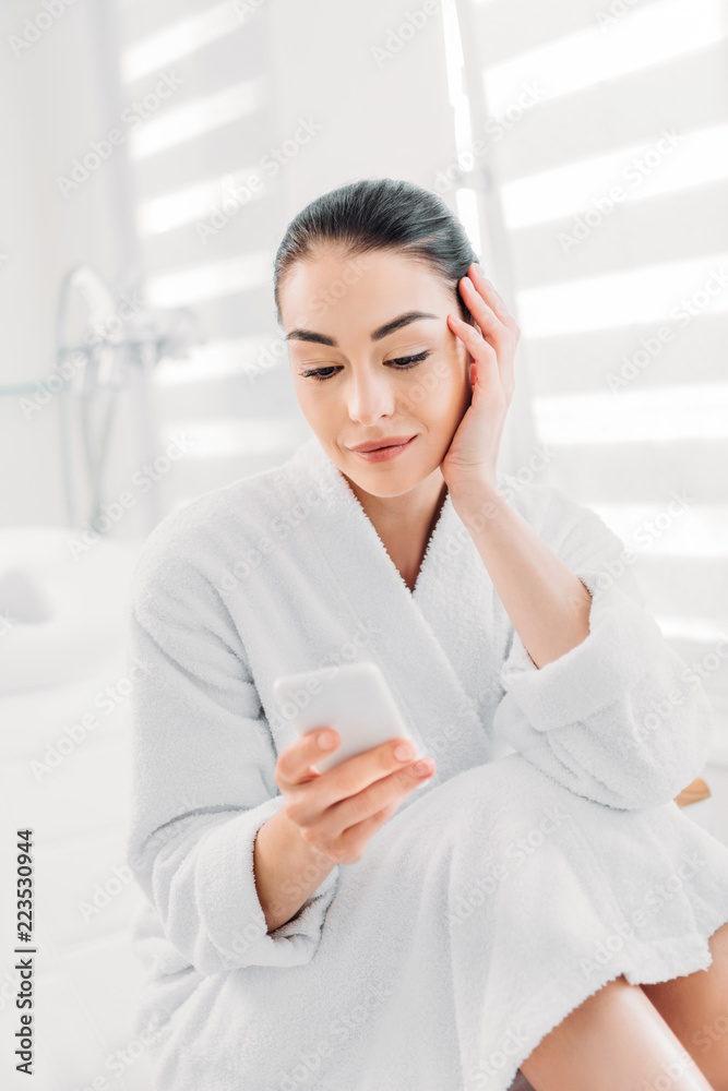 portrait of woman in white bathrobe using smartphone in spa salon portrait of woman in white bathrobe using smartphone in spa salon