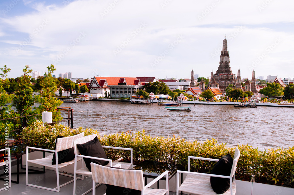 Bangkok outdoor restaurant with dinner tables by river with Wat Arun temple view