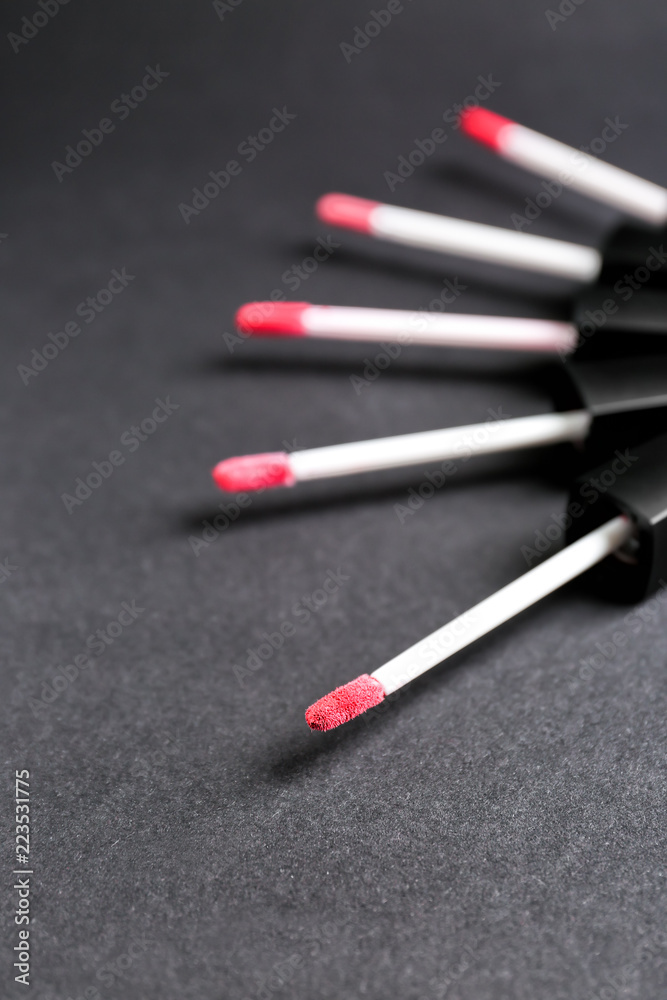 Brushes with color lipstick on grey background
