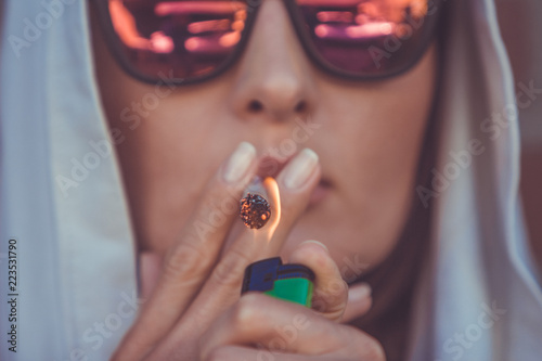 Young woman smoking marijuana joint - medical marijuana use and legalization of cannabis concepts - closeup of lighting a weed cigarette in Amsterdam (Holland - Netherlands)
