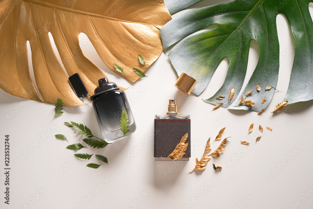 Bottles with perfumes and tropical leaves on light background - obrazy, fototapety, plakaty 
