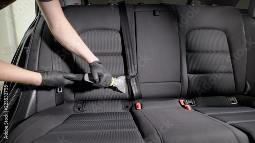Faceless employee carefully vacuuming car seat