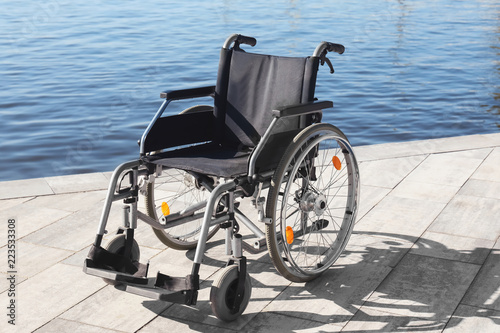 Empty modern wheelchair near river on embankment