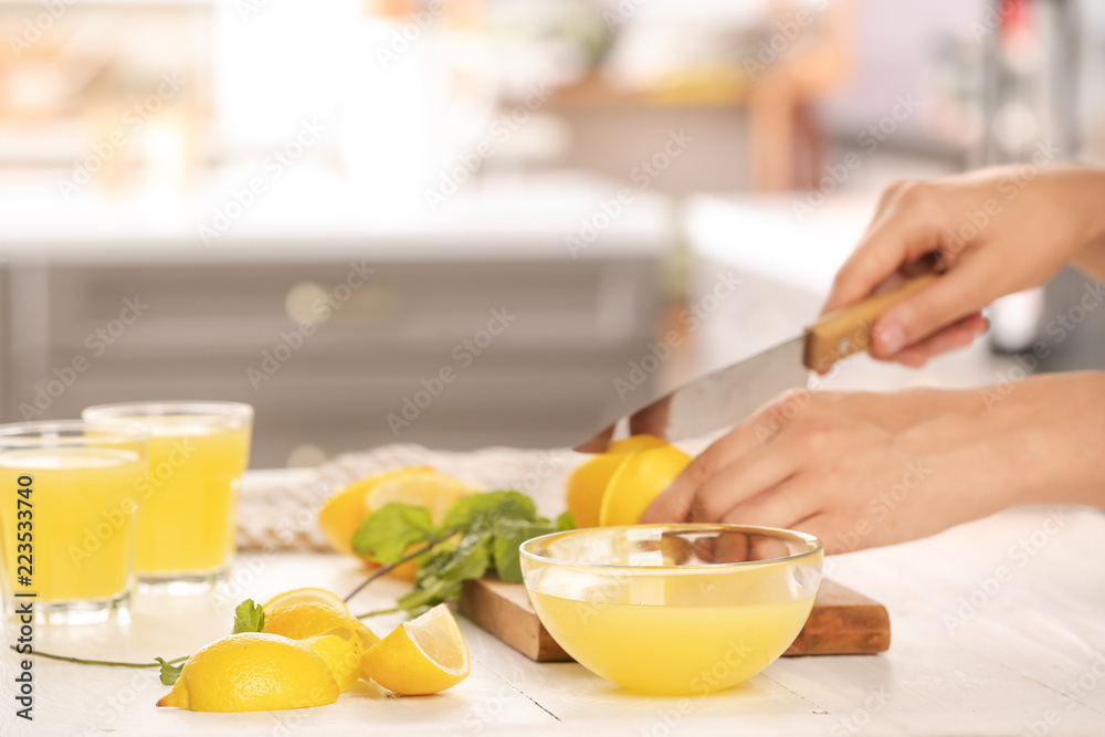 Woman cutting fresh lemon for juice at table Woman cutting fresh lemon for juice at table