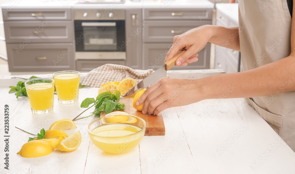 Woman cutting fresh lemon for juice at table Woman cutting fresh lemon for juice at table