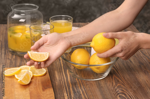Woman preparing fresh lemon juice at wooden table