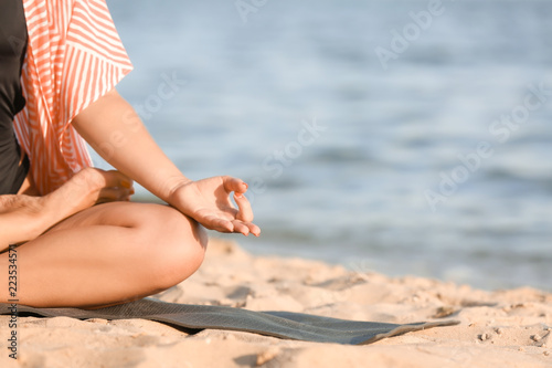 Woman practicing yoga on sea shore, closeup