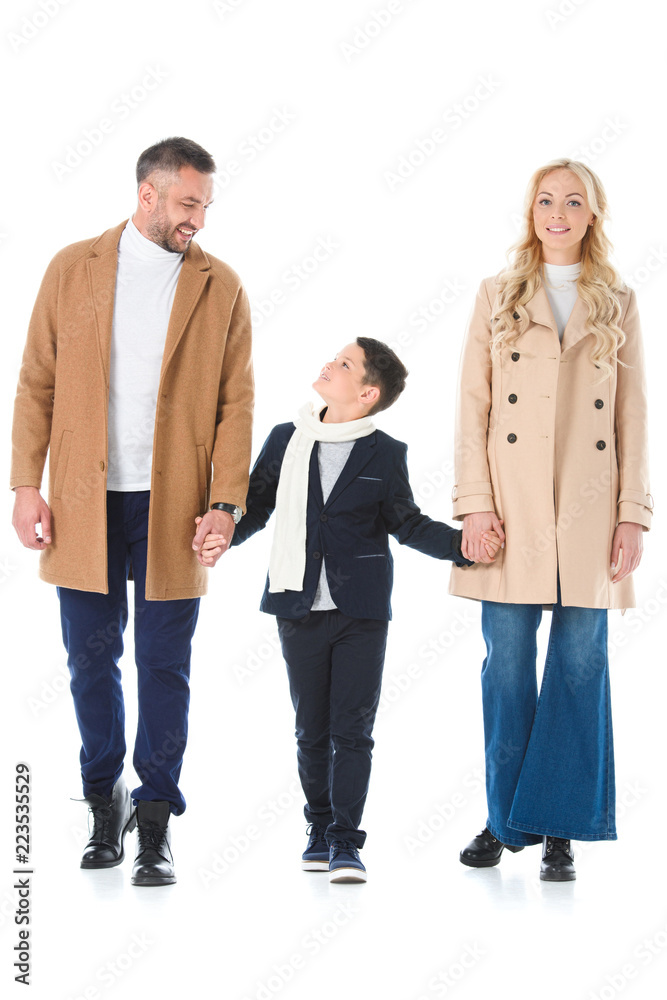 Obraz premium parents in beige coats holding hands with son, isolated on white