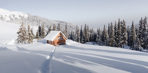 Fantastic winter landscape with wooden house in snowy mountains. Christmas holiday concept. Carpathians mountain, Ukraine, Europe
