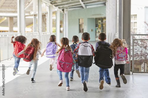 Elementary school kids run from camera in corridor, close up photo
